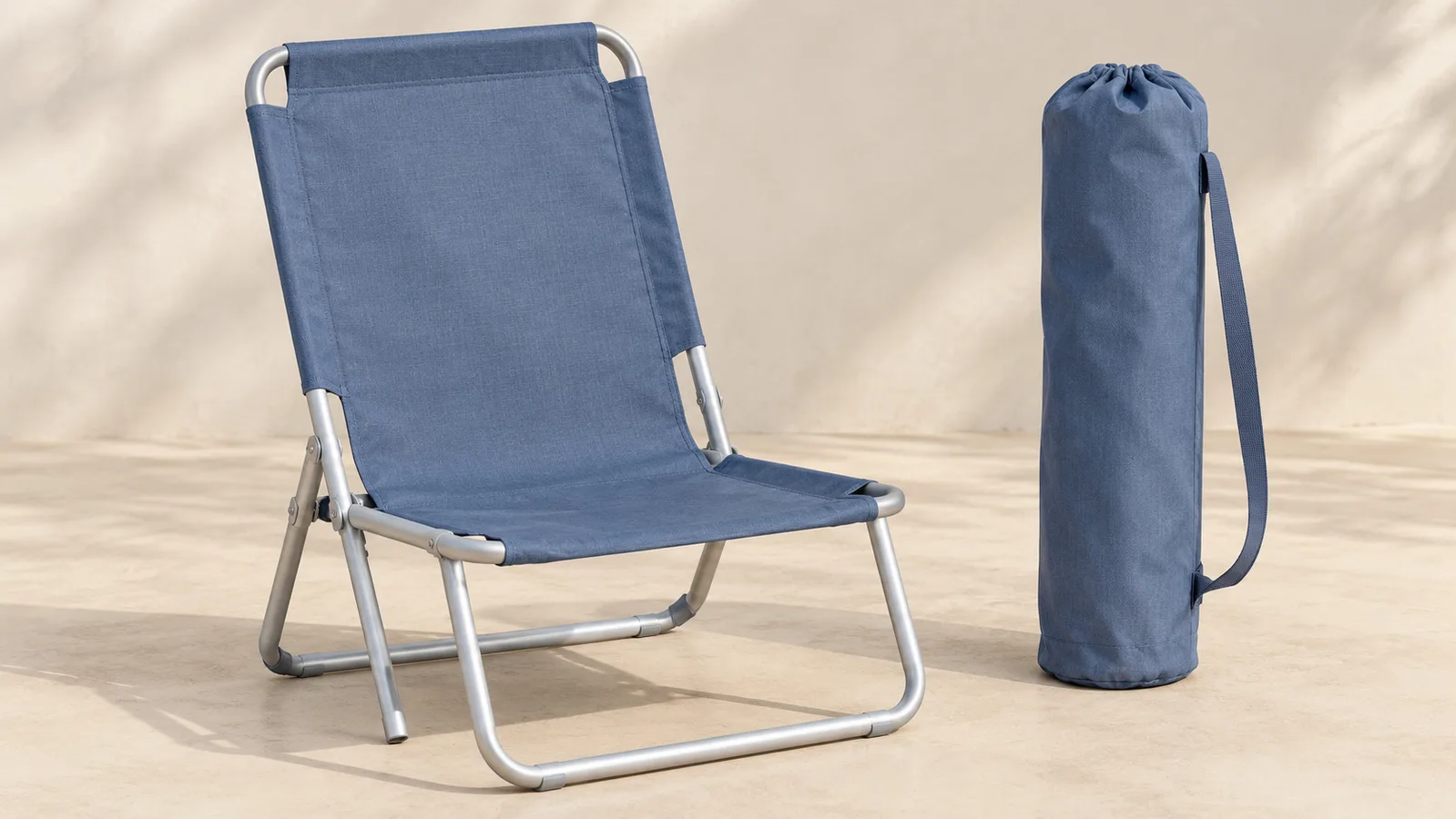 Ein schlichter, zusammenklappbarer Strandstuhl, geöffnet neben der passenden, verpackten Tragetasche